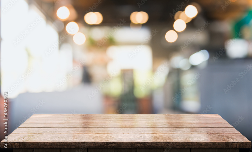 Empty wooden table top with lights bokeh on blur restaurant background.