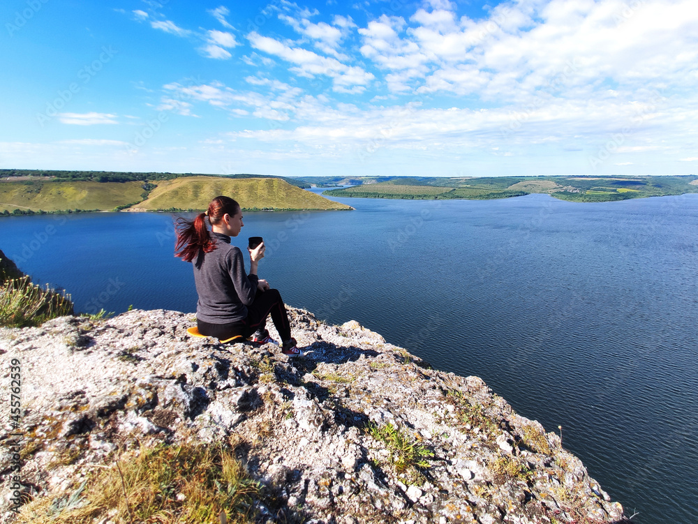Woman relaxing on mountain and looking at Dnister river, Bakota, Ukraine