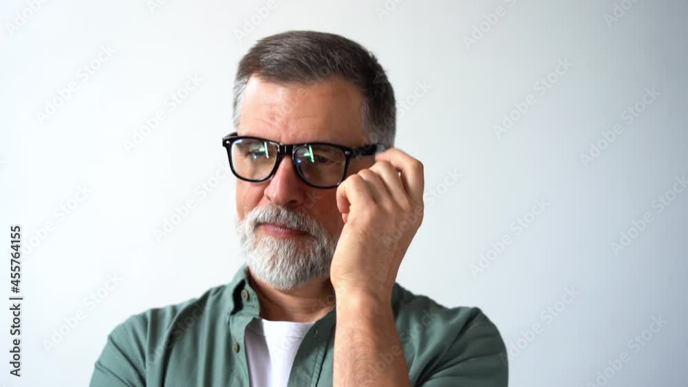 Friendly looking retired senior man taking off his glasses and smiling cheerfully while looking into the camera Friendly looking retired senior man taking off his glasses and smiling cheerfully while looking into the camera