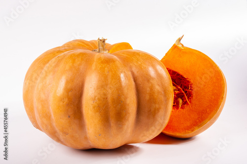 Whole fresh orange big pumpkin and slice of pumpkin on white background, closeup. Organic agricultural product, ingredients for cooking, healthy food vegan.