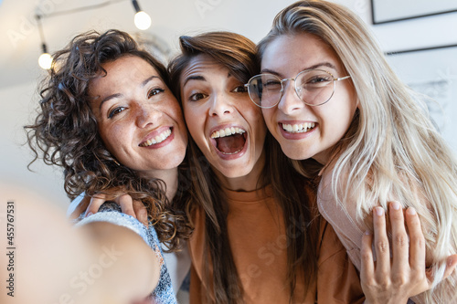 Female friends taking group selfie for social media.