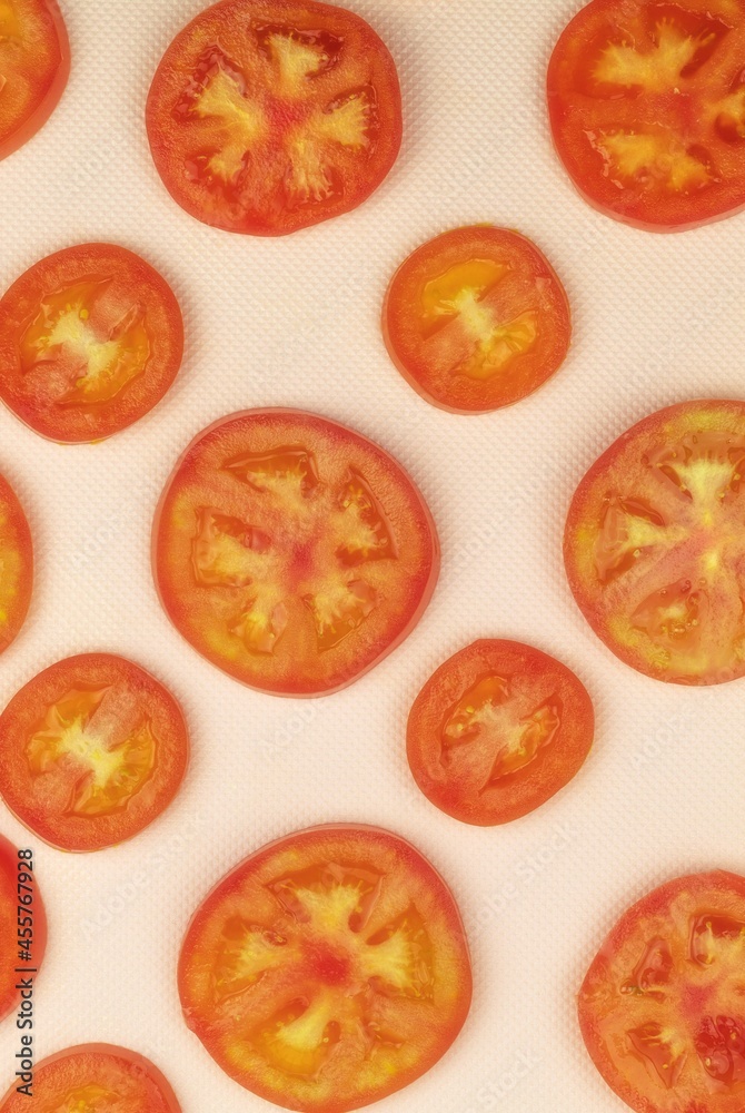 Fresh slices of red tomato are lying on a pink background Fresh slices of red tomato are lying on a pink background