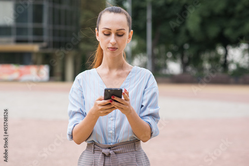 Portrait of attractive and beautiful Caucasian business woman. Lady is using a smartphone. Business and networking concept.