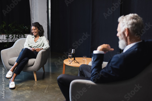 Canvastavla happy african american journalist laughing near blurred businessman during talk