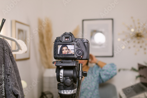 Smiling Hispanic blogger shooting video on camera photo