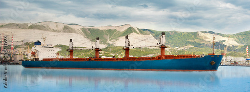 A old bulk carrier or bulker sails in the sea to trade around the world. Cargo ship at the trade port. A view from the yacht, close-up.