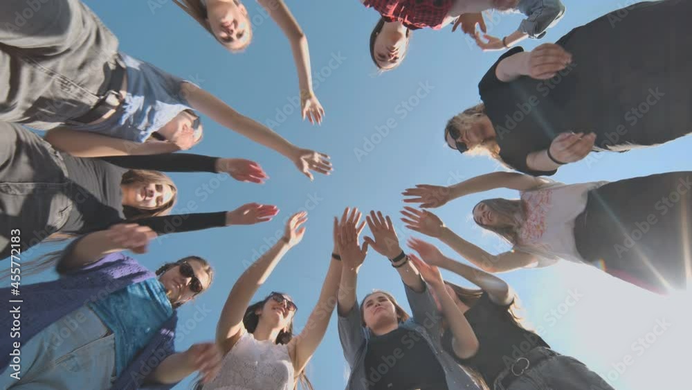 Eleven cheerful girlfriends make their hands together on a sunny day.