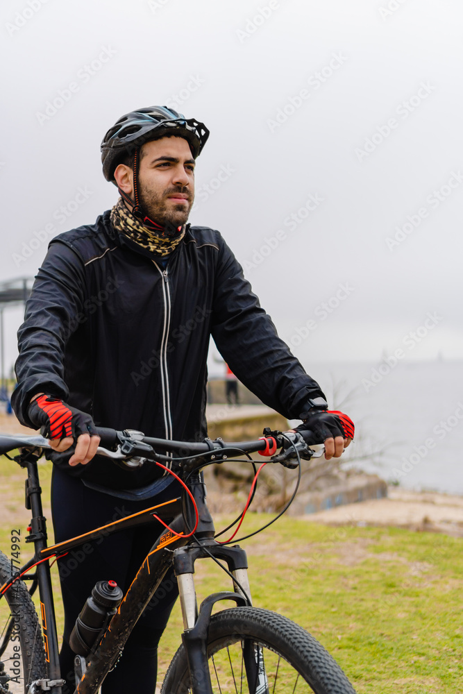 young latino hispanic male athlete with his bike and helmet walking in the morning, vertical photo young latino hispanic male athlete with his bike and helmet walking in the morning, vertical photo