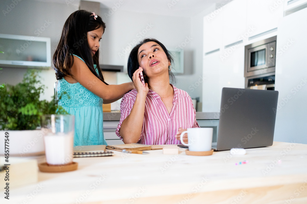 Mother working at home accompanied by her daughter Mother working at home accompanied by her daughter