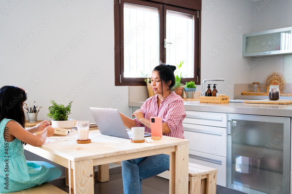 Mother working and having breakfast with her daughter at home Mother working and having breakfast with her daughter at home