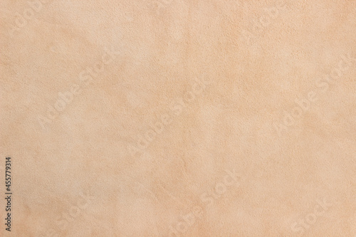 Light beige matte background of suede fabric, closeup. Velvet texture of seamless sand leather. Soft beige leather texture with print as background.