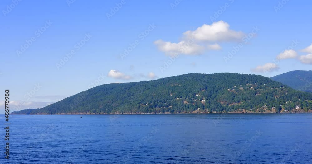 Establishing shot of ocean view with mountains, blue sky and white clouds in slow motion at summer day in Vancouver, Canada, North America. Day time on Sept 2021. Still camera. ProRes 422 HQ. Establishing shot of ocean view with mountains, blue sky and white clouds in slow motion at summer day in Vancouver, Canada, North America. Day time on Sept 2021. Still camera. ProRes 422 HQ.