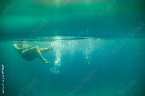 close up of woman's feet underwater flowing and floating while swimming in the sea with a flotation device known as pool noodle