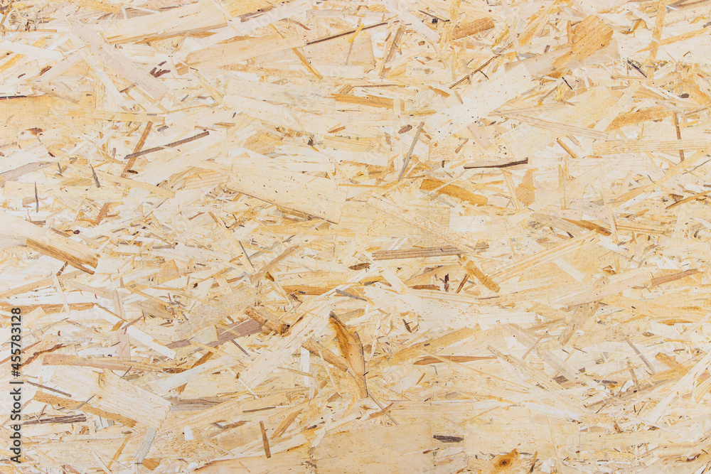 Pressed wooden shavings panel background. OSB sheet is made of brown wood chips pressed together into a wooden floor.