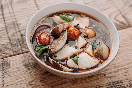 Bowl of spicy seafood soup on a rustic wooden table. photo