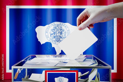 Photography Wyoming flag, hand dropping ballot card into a box - voting, election concept -