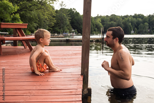 Dad persuading son to swim in the lake photo