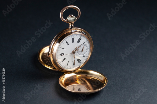 Antique gold pocket watch with white dial and exposed mechanical movement.