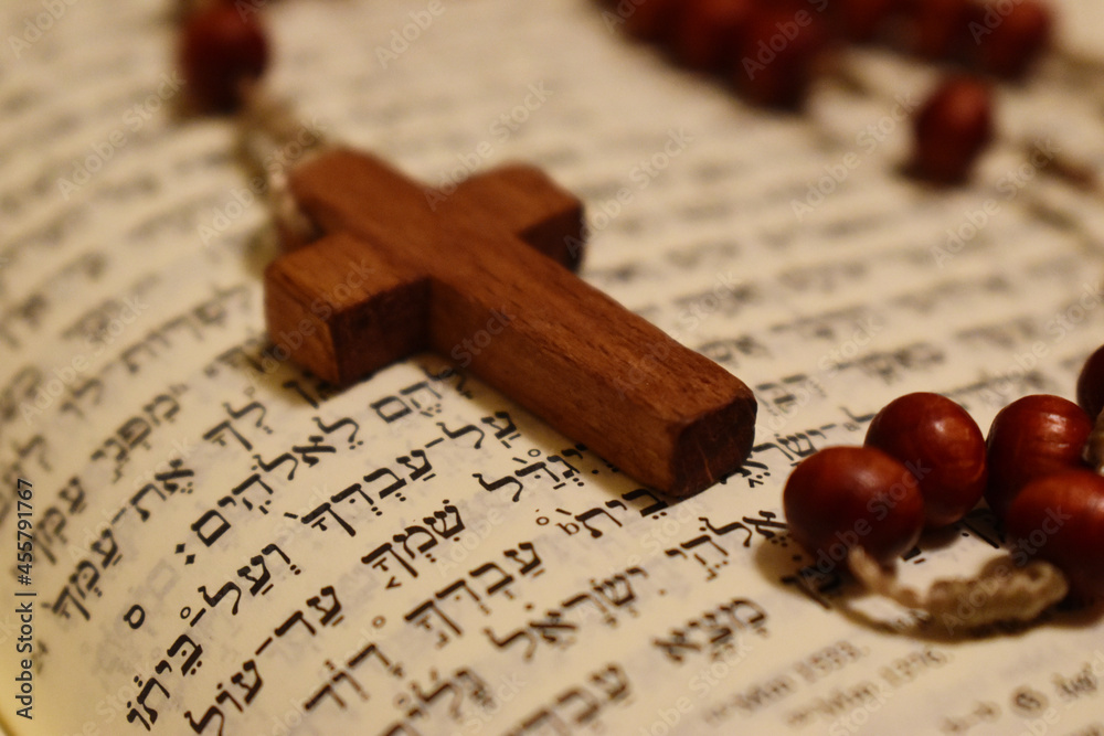 Obraz premium Drewniany krzyżyk na hebrajskim tekście biblijnym