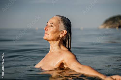 Active mature woman bathing in the sea in the morning photo