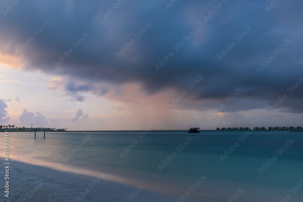 Sunset light shining on ocean waves. Maldives beach. July 2021