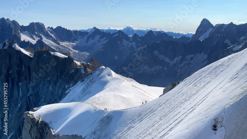 4K French Alps mountains peaks panorama view with climbers silhouettes as roping team descending on the snowy slope under Aiguille du Midi 3842m. Beauty of Nature and extreme people activity concept