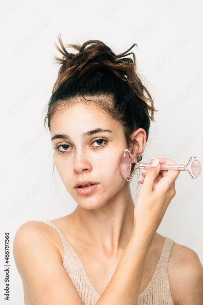 Young Caucasian Woman With No Make Up Using Face Roller Young Caucasian Woman With No Make Up Using Face Roller