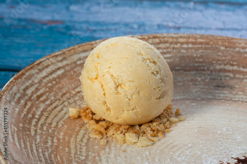 scoop of vanilla ice cream and almonds on a plate and blue background
