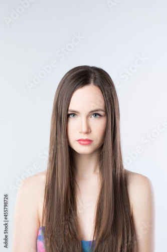 Beautiful serious brunette woman with long hair on a white background