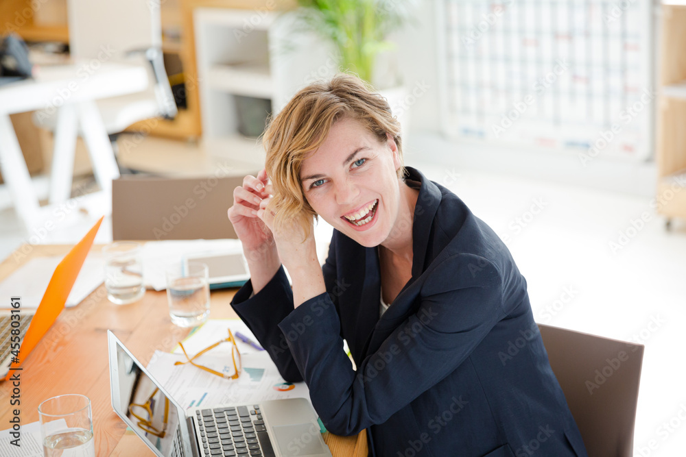 Obraz premium Portrait of woman sitting at desk with laptop in office