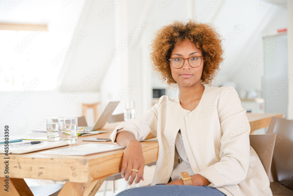 Portrait of woman sitting at desk in office and smiling Portrait of woman sitting at desk in office and smiling