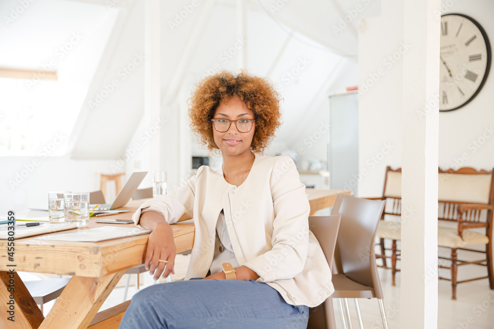 Portrait of woman sitting at desk in office and smiling Portrait of woman sitting at desk in office and smiling