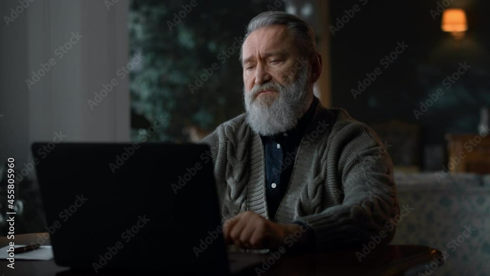 Focused senior man talking during video call on laptop computer