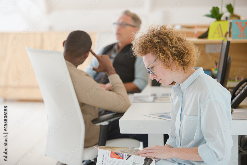 Fototapeta premium Portrait of woman reading magazine in office