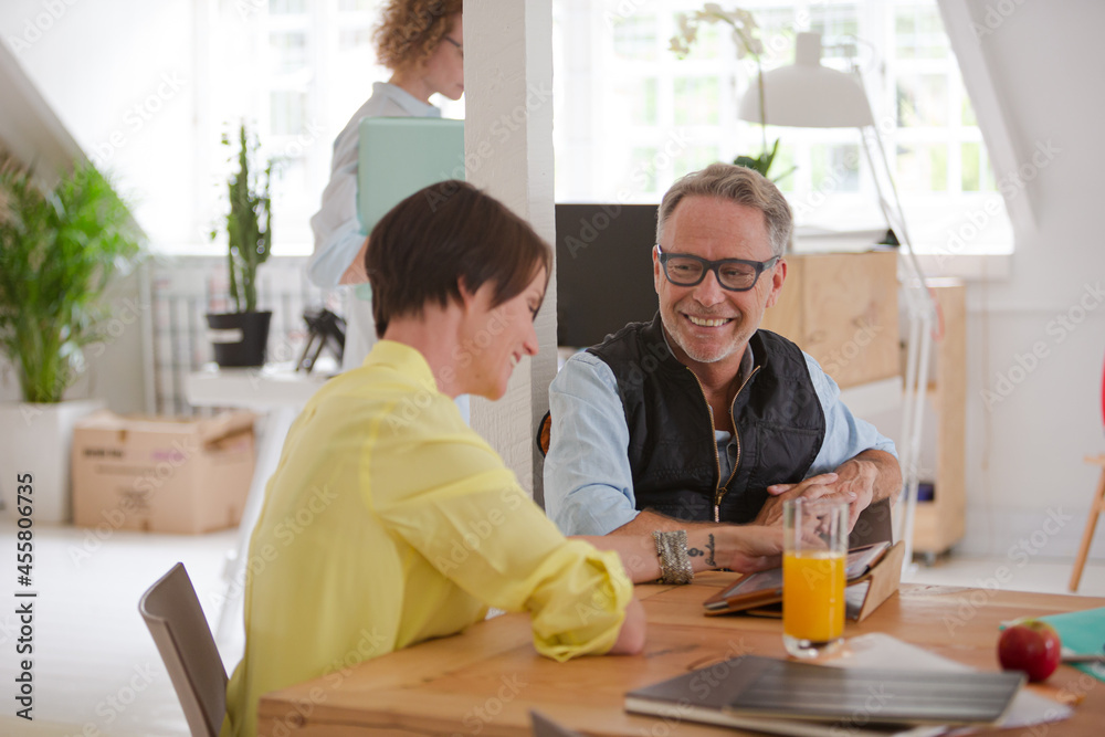Man and woman sitting in office,smiling and talking Man and woman sitting in office,smiling and talking