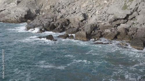 Water splashing. Water beats against seashore. Sea waves of blue water beat against the coastal rocks. An infinite number of splashes, drops of sea water and white foam are scattered. Novy Svet