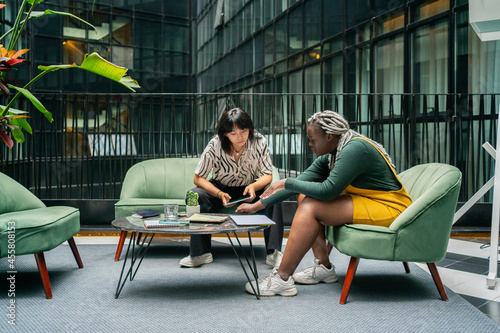 Two Women Sitting On A Couch In A Coworking Workplace.  photo