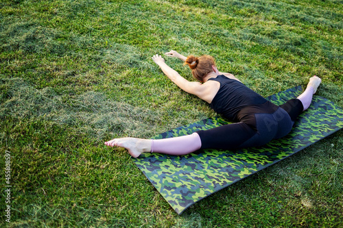 Sporty beautiful young woman practicing yoga, doing Half Splits Exercise, working out wearing black sportswear, studio, full length