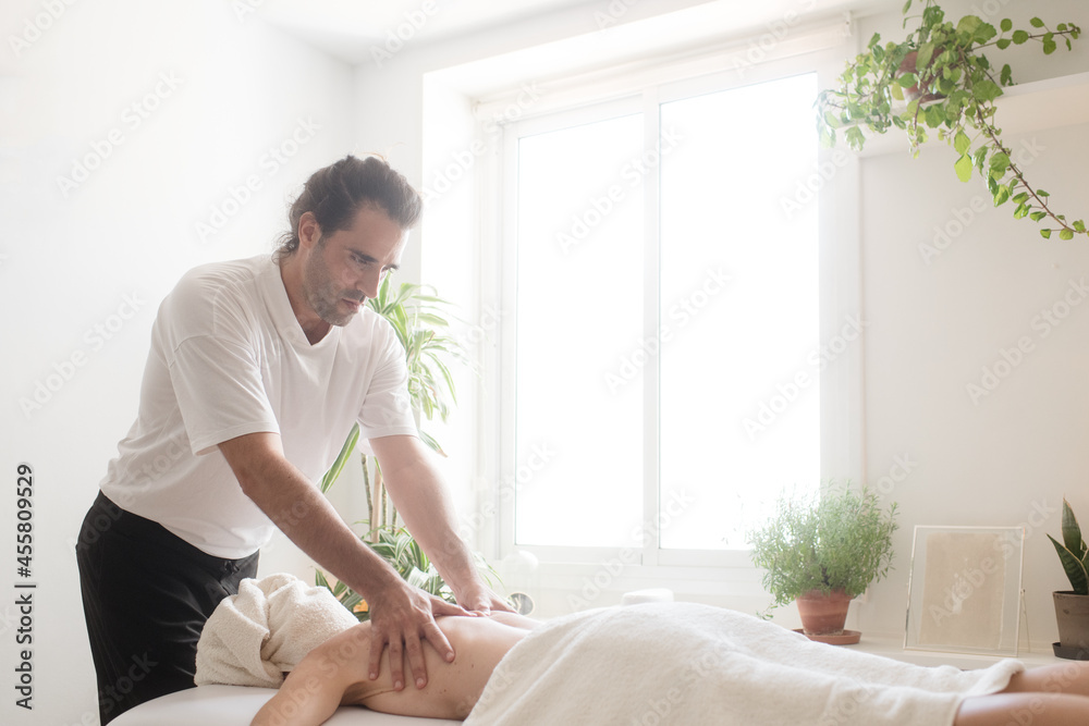 Focussed massage therapist working on patient's back Focussed massage therapist working on patient's back