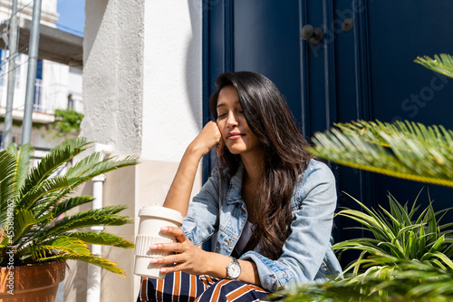 Pensive young woman meditating in doorway with closed eyes photo