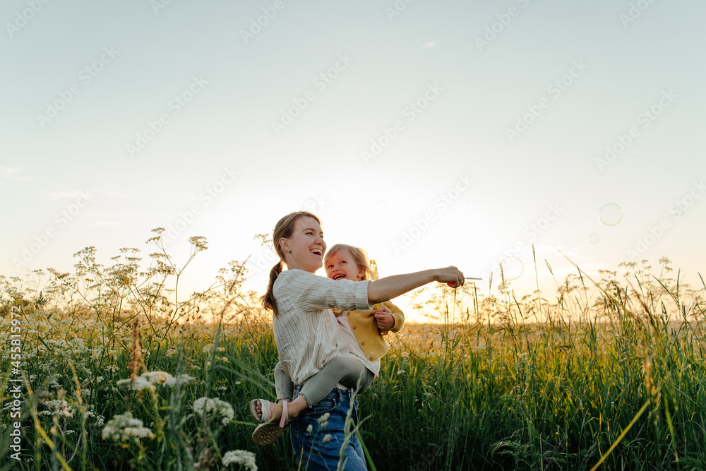 Mother and daughter blowing bubbles in meadow Mother and daughter blowing bubbles in meadow