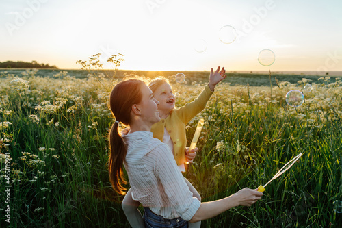 Smiling child with mom playing with blowing bubbles photo