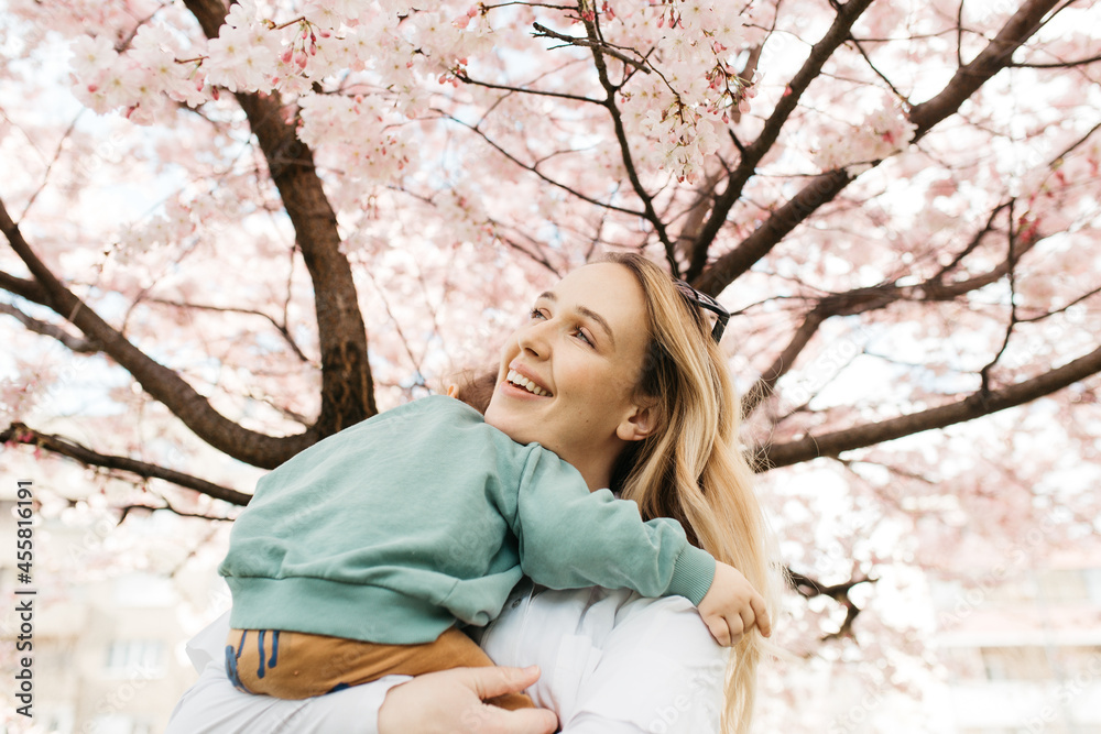 Mother holding a child under blossoming tree. Mother holding a child under blossoming tree.