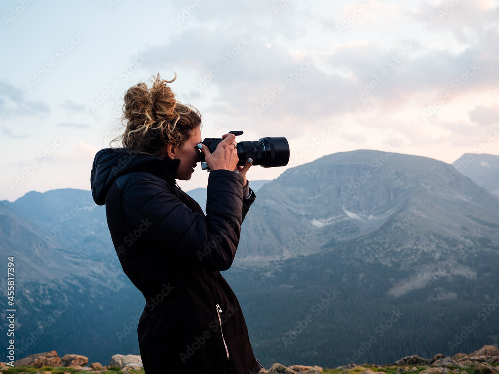 Young girl taking photos during sunset in the Rocky Mountains of Colorado.