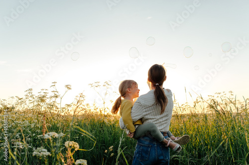 Unrecognizable mother and daughter blowing bubbles 