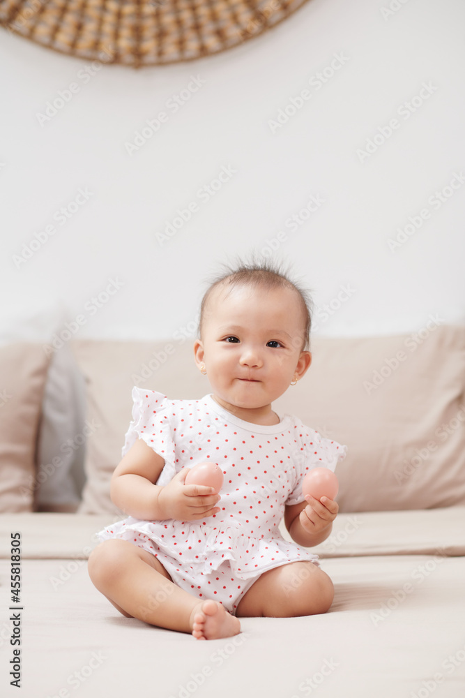 Adorable toddler having fun, sitting on bed and playing with toy. Adorable toddler having fun, sitting on bed and playing with toy.
