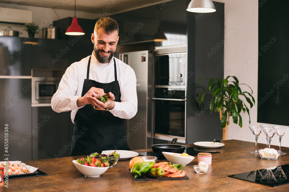 Positive chef preparing fresh herbs for dish Positive chef preparing fresh herbs for dish