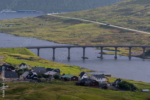 Beautiful view of a small village  in the Faroe Islands, and its amazing bridge with its :churchs, grass roofs and colorful Houses in front of the ocean 