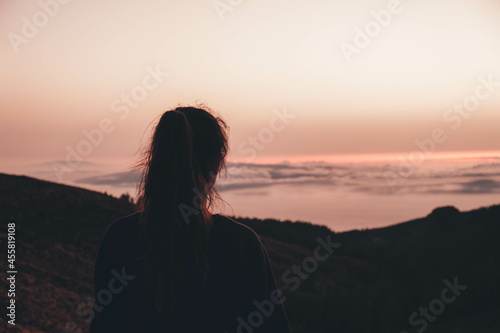 Chica de espaldas contemplando un mar de nubes durante el atardecer en el Teide, Tenerife © Sergio