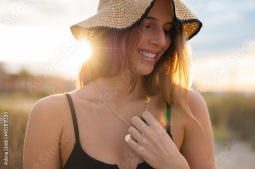 Happy woman touching necklace on summer day photo
